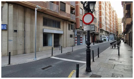 Calle urbana con acceso restringido mediante señalización y elementos físicos de control.
